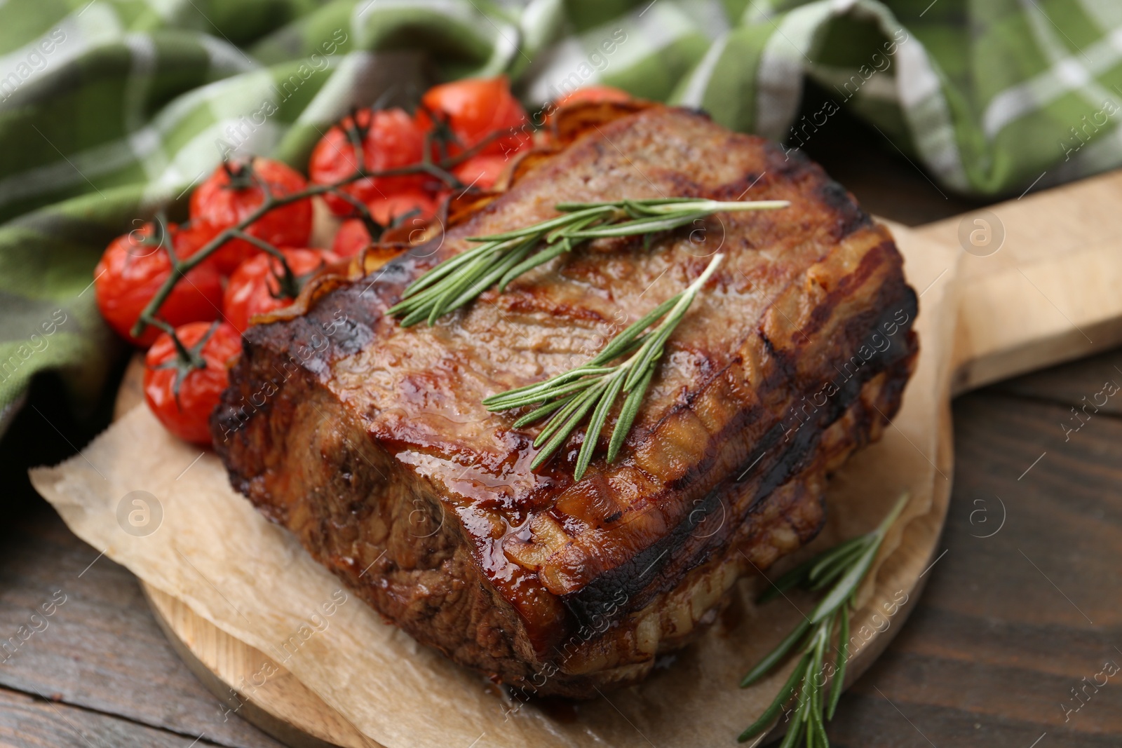 Photo of Delicious roast beef with rosemary and tomatoes on wooden table, closeup