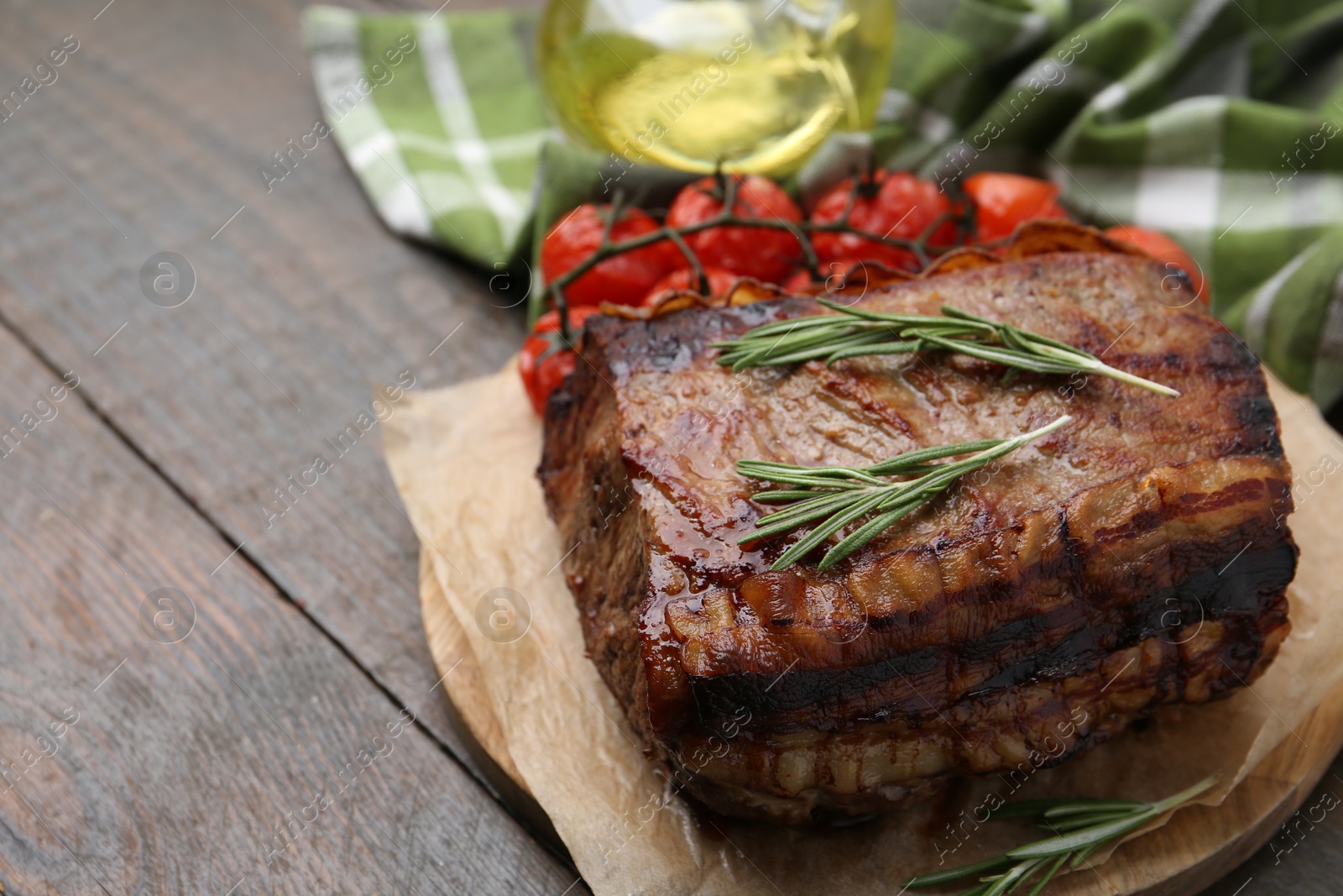 Delicious roast beef with rosemary and tomatoes on wooden table, closeup Photo of Delicious roast beef with rosemary and tomatoes on wooden table, closeup