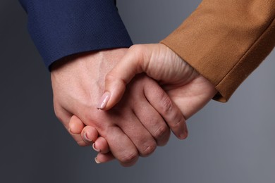 Photo of Man and woman holding hands together on grey background, closeup
