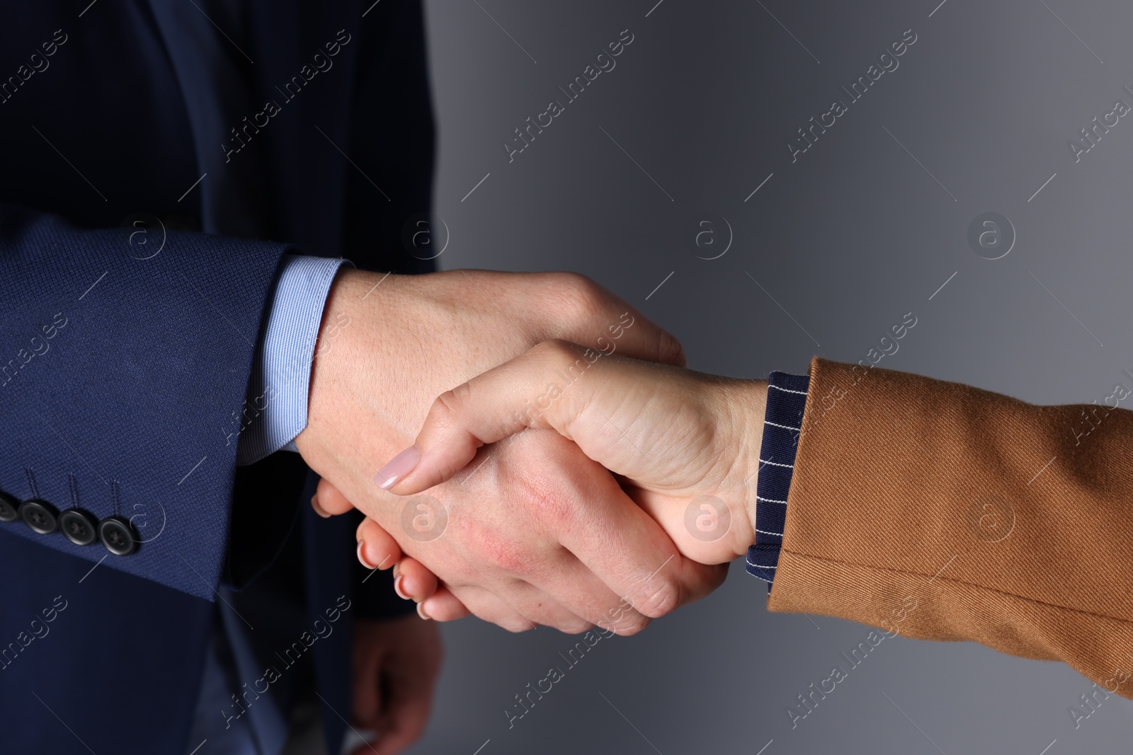 Photo of Business partners shaking hands on grey background, closeup