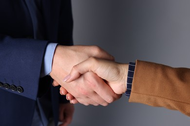 Photo of Business partners shaking hands on grey background, closeup