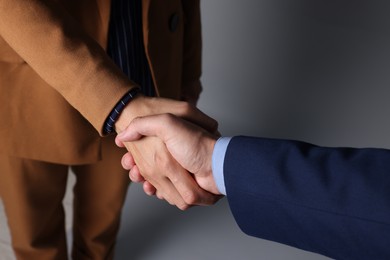 Photo of Business partners shaking hands on grey background, closeup
