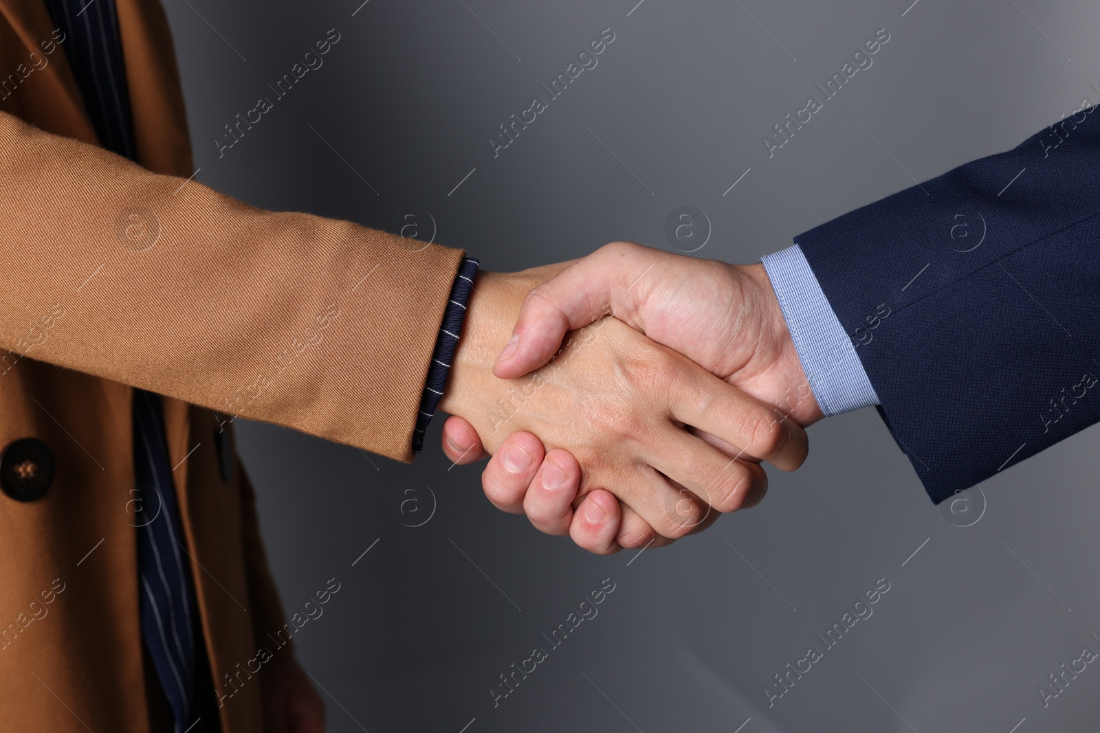 Photo of Business partners shaking hands on grey background, closeup