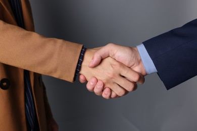 Photo of Business partners shaking hands on grey background, closeup