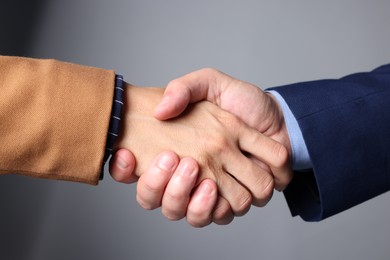 Photo of Business partners shaking hands on grey background, closeup