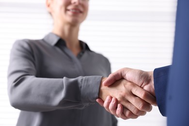 Photo of Business partners shaking hands indoors, selective focus
