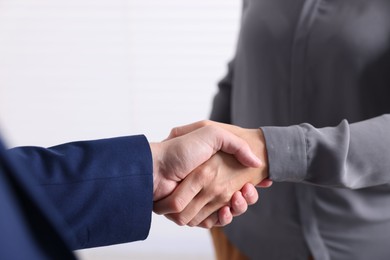 Photo of Business partners shaking hands indoors, closeup view