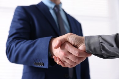 Photo of Business partners shaking hands indoors, closeup view