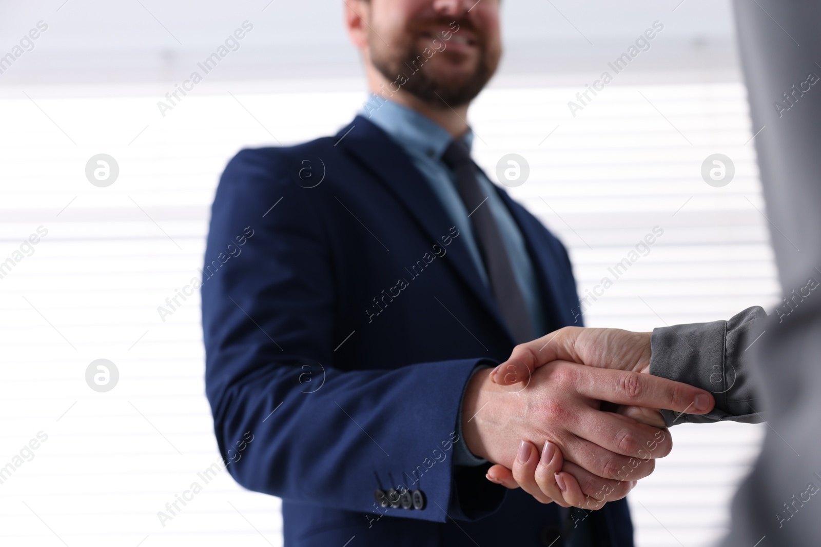 Photo of Business partners shaking hands indoors, selective focus