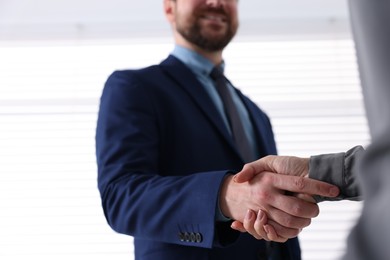 Photo of Business partners shaking hands indoors, selective focus