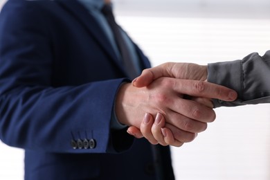 Photo of Business partners shaking hands indoors, closeup view