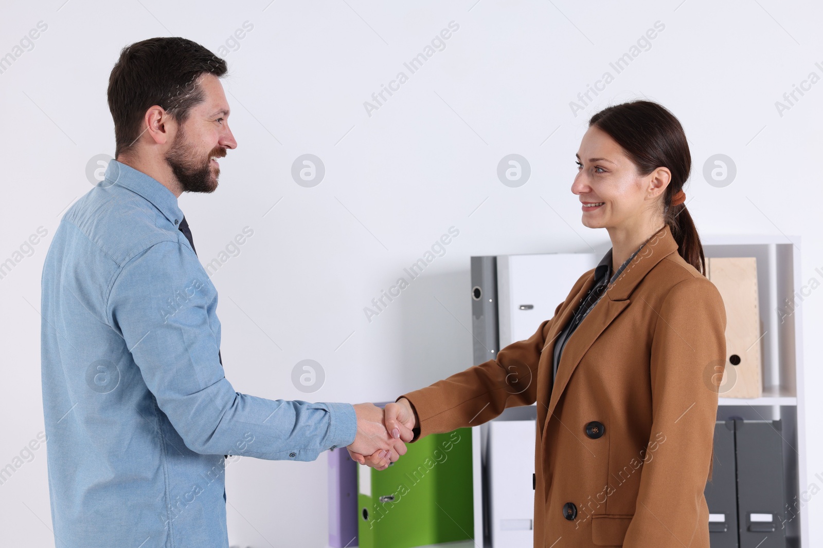 Photo of Happy business partners shaking hands in office