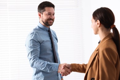 Photo of Man and woman shaking hands in office