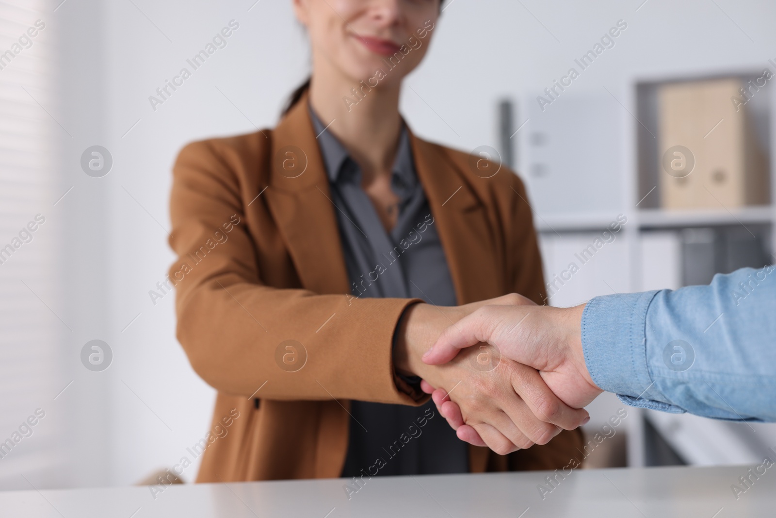 Photo of Business partners shaking hands at table indoors, closeup