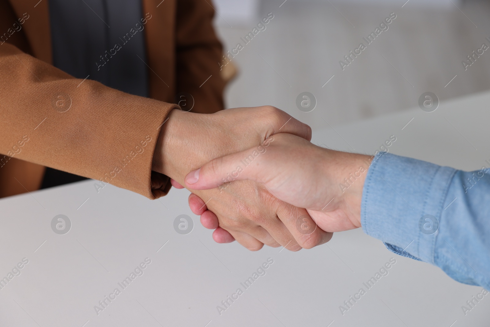 Photo of Business partners shaking hands at table indoors, closeup