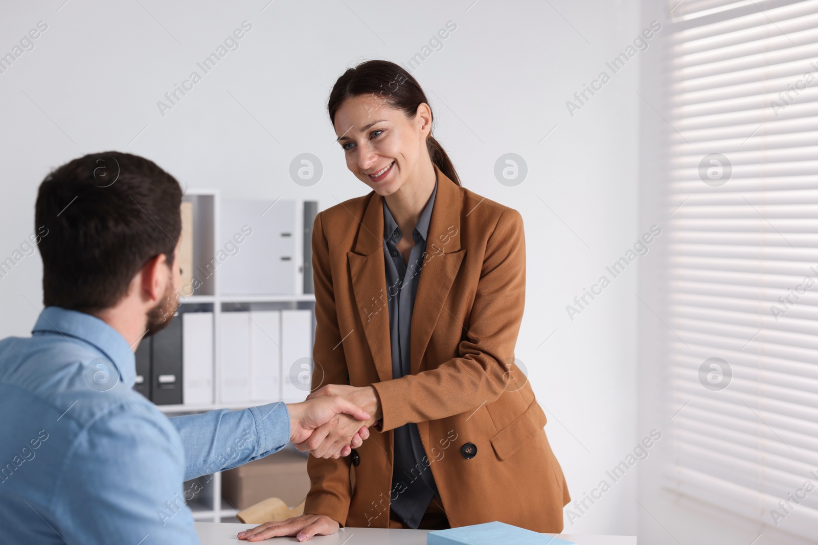 Photo of Business partners shaking hands at table indoors, space for text