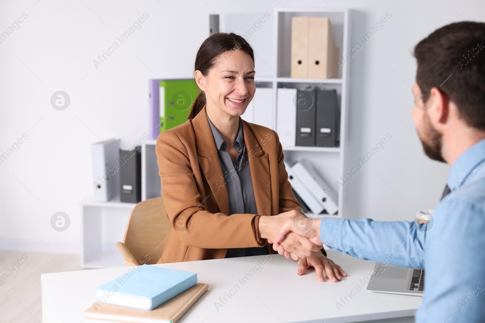 Photo of Business partners shaking hands at table indoors