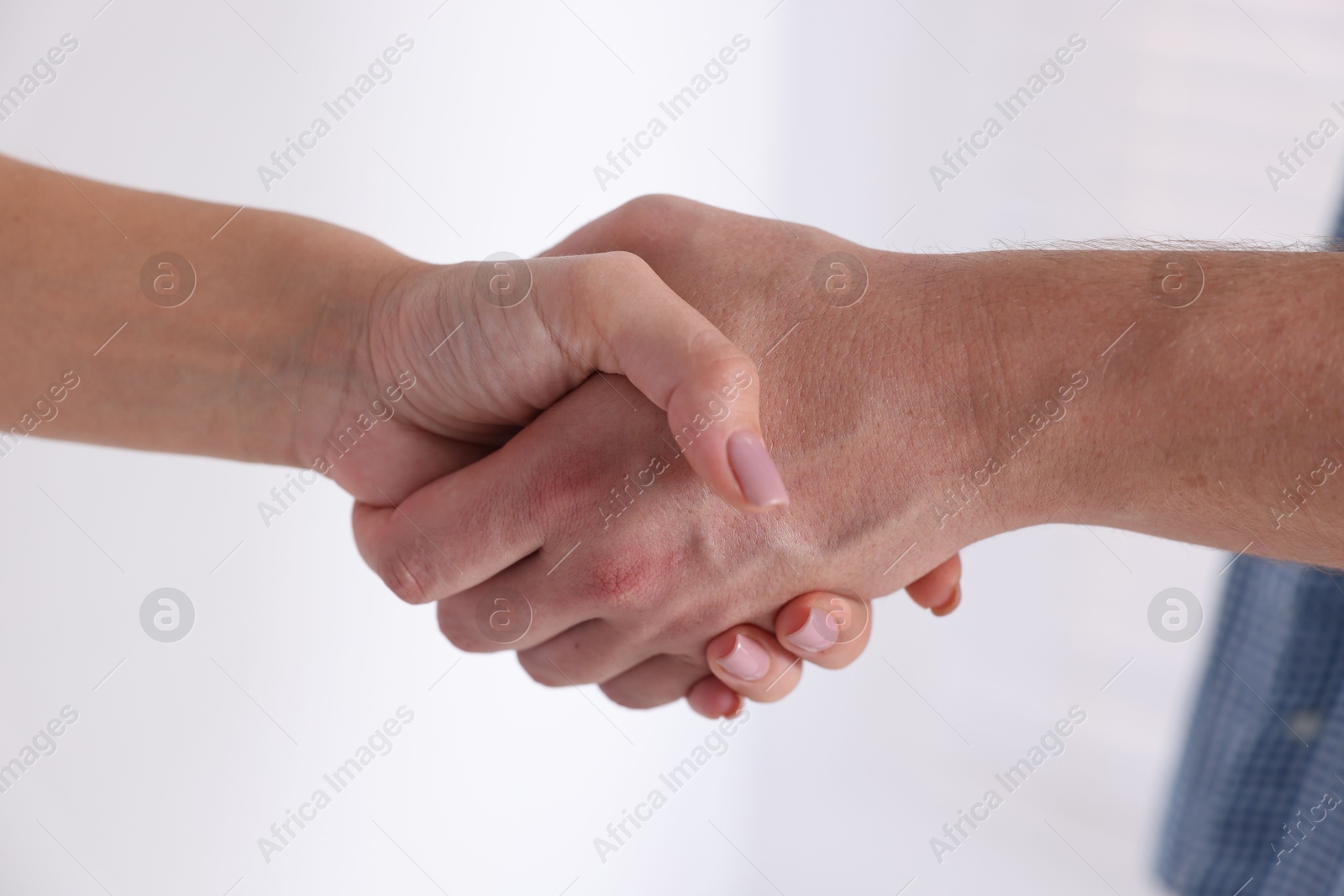 Photo of Man and woman shaking hands near window indoors, closeup