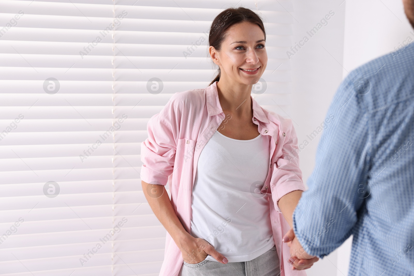 Photo of Man and woman shaking hands indoors, space for text