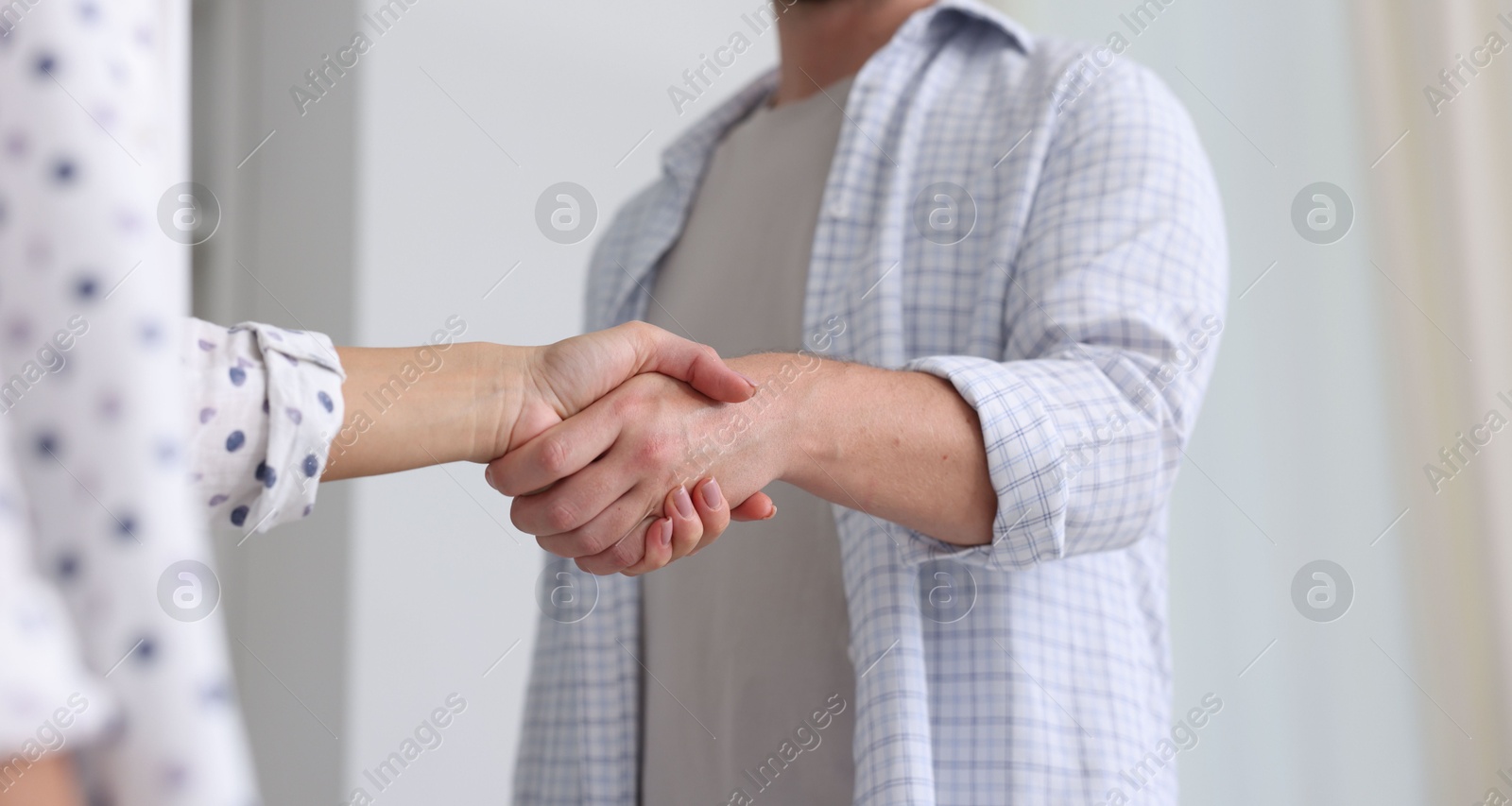 Photo of Man and woman shaking hands indoors, closeup