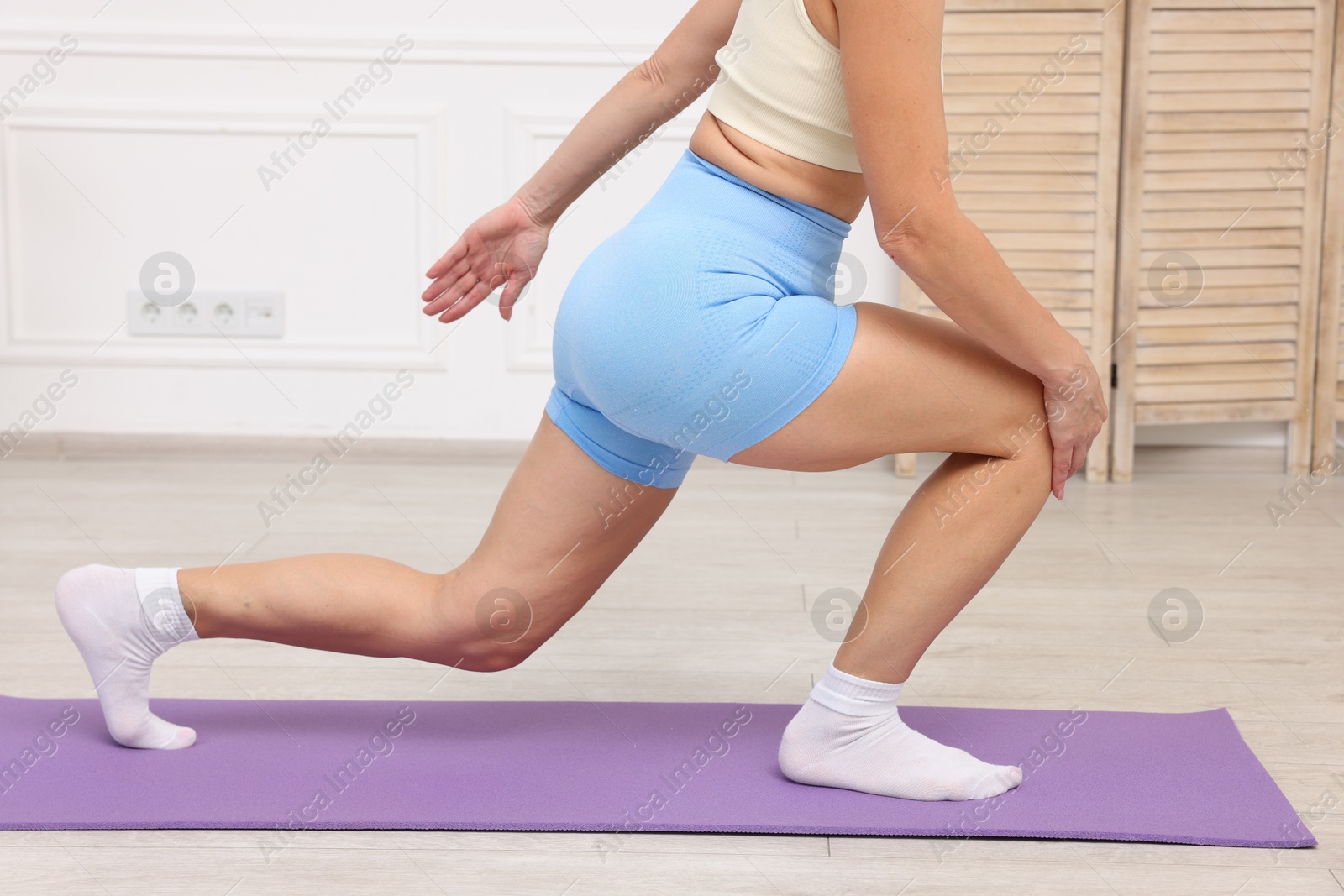 Photo of Mature woman stretching on mat at home, closeup