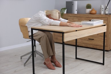 Photo of Mature woman stretching at table in office