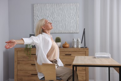 Photo of Mature woman stretching at table in office