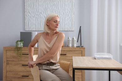 Photo of Mature woman stretching on chair in office