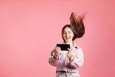 Photo of Happy woman in jacket with beautiful long hair using smartphone on pink background. Space for text