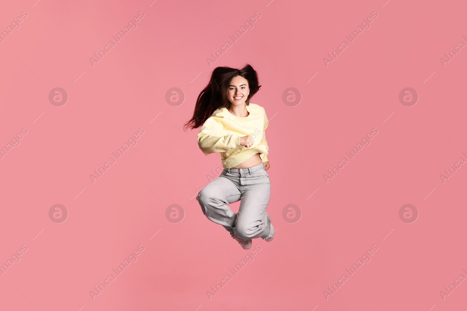 Photo of Happy woman with beautiful long hair jumping on pink background