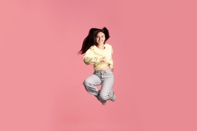 Photo of Happy woman with beautiful long hair jumping on pink background