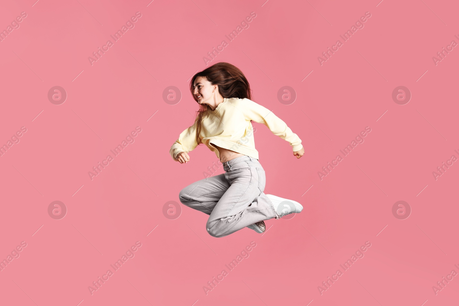 Photo of Happy woman with beautiful long hair jumping on pink background