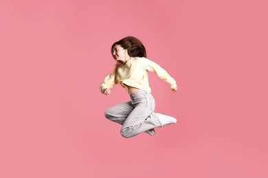 Photo of Happy woman with beautiful long hair jumping on pink background