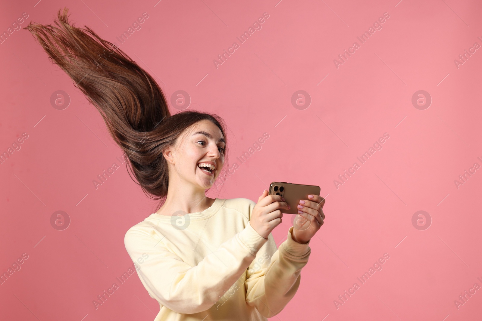 Photo of Happy woman with beautiful long hair using smartphone on pink background