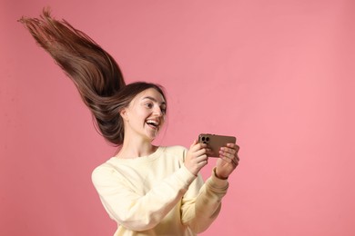 Photo of Happy woman with beautiful long hair using smartphone on pink background