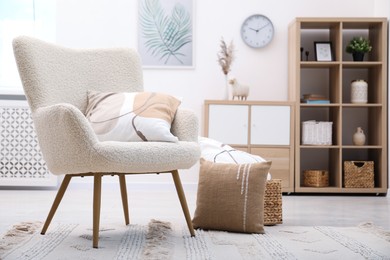 Photo of White armchair with pillow indoors. Interior design
