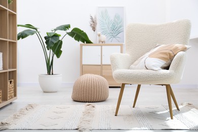 Photo of White armchair with pillow indoors. Interior design