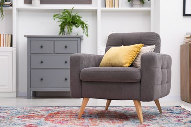 Photo of Grey armchair with pillows indoors. Interior design