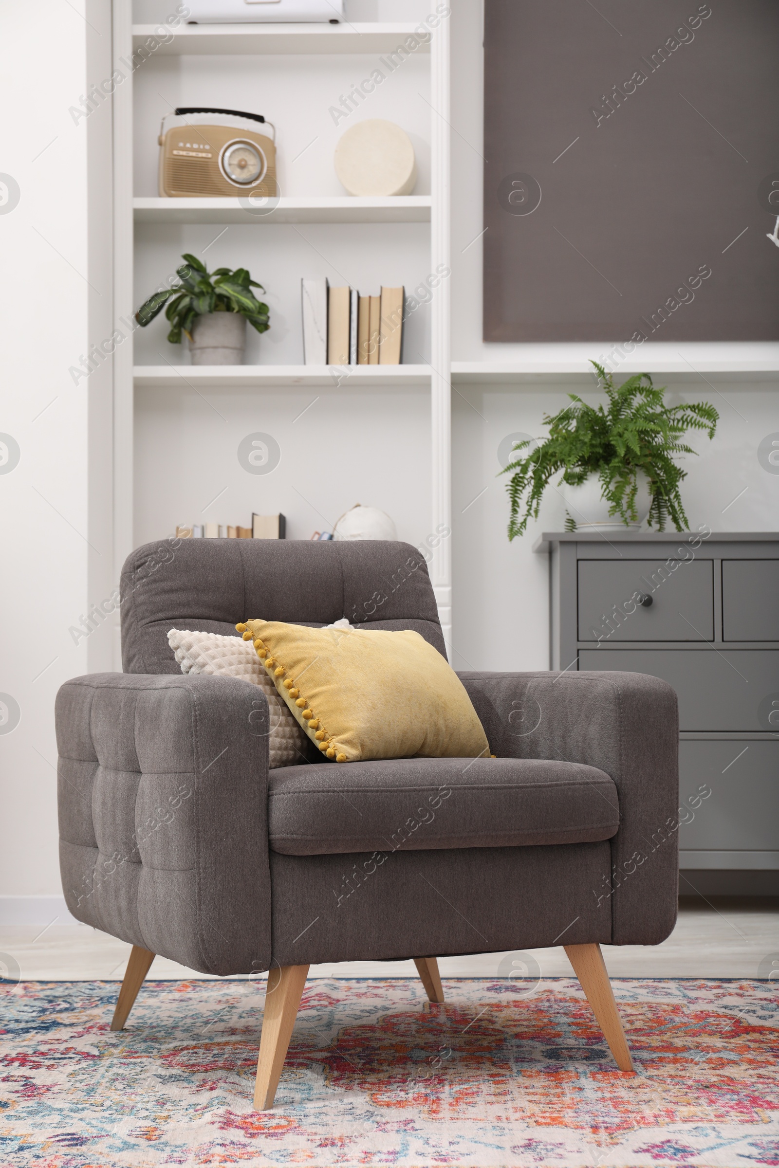 Photo of Grey armchair with pillows indoors. Interior design