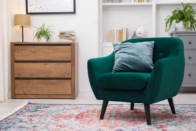 Photo of Stylish armchair with pillow, shelving unit and chest of drawers indoors. Interior design