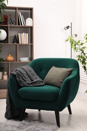 Photo of Stylish armchair with pillow and blanket indoors. Interior design