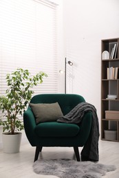 Photo of Stylish armchair with pillow and blanket indoors. Interior design