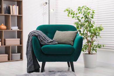 Photo of Stylish armchair with pillow and blanket indoors. Interior design