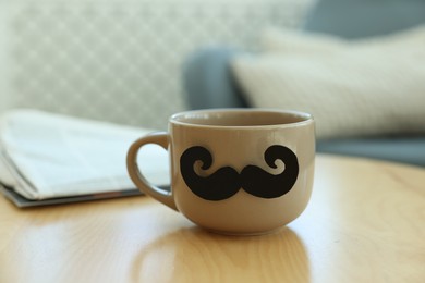 Photo of Happy Father's Day. Cup with mustache on wooden table indoors, closeup