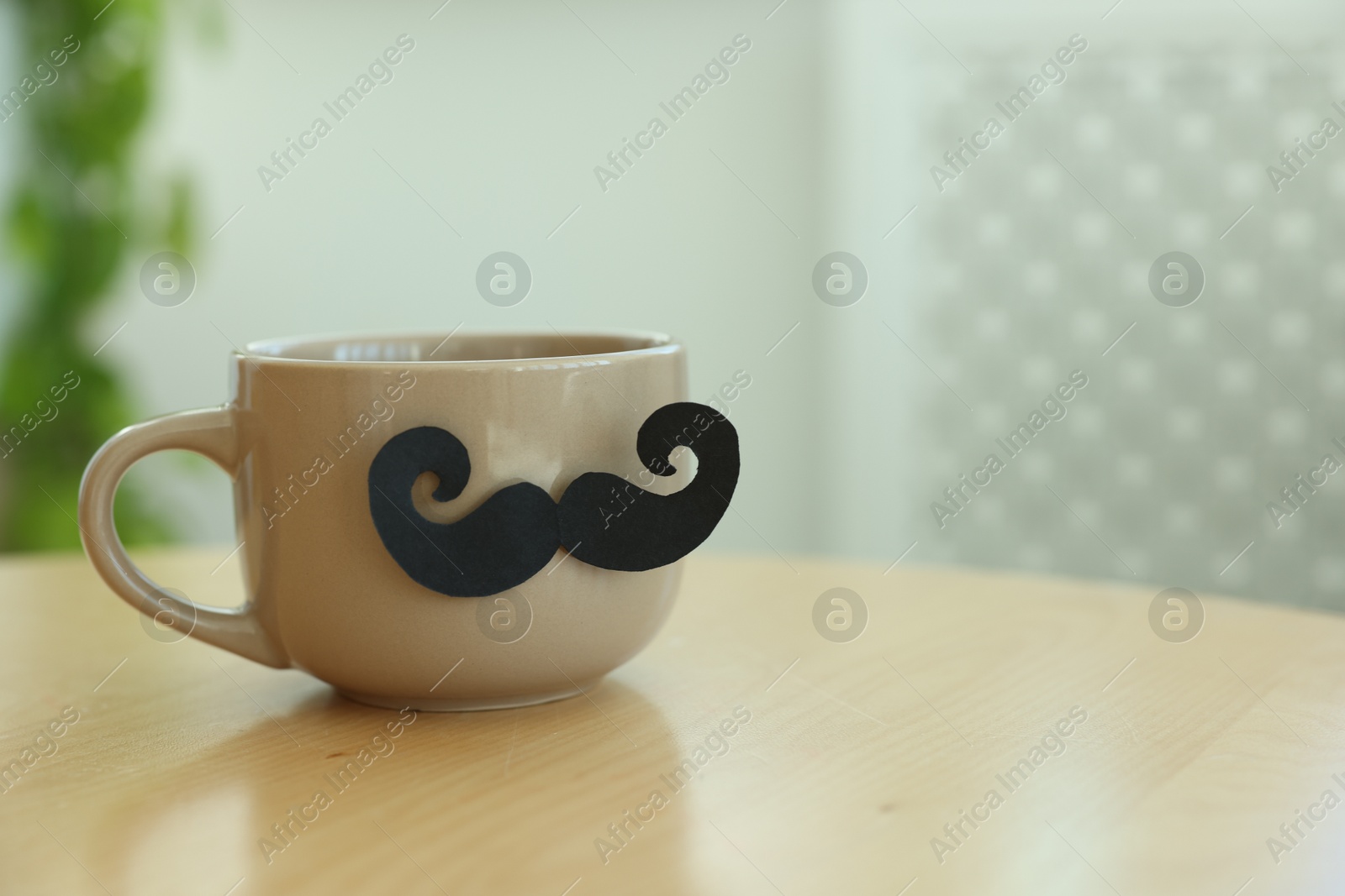 Happy Father's Day. Cup with mustache on wooden table indoors, closeup. Space for text Photo of Happy Father's Day. Cup with mustache on wooden table indoors, closeup. Space for text