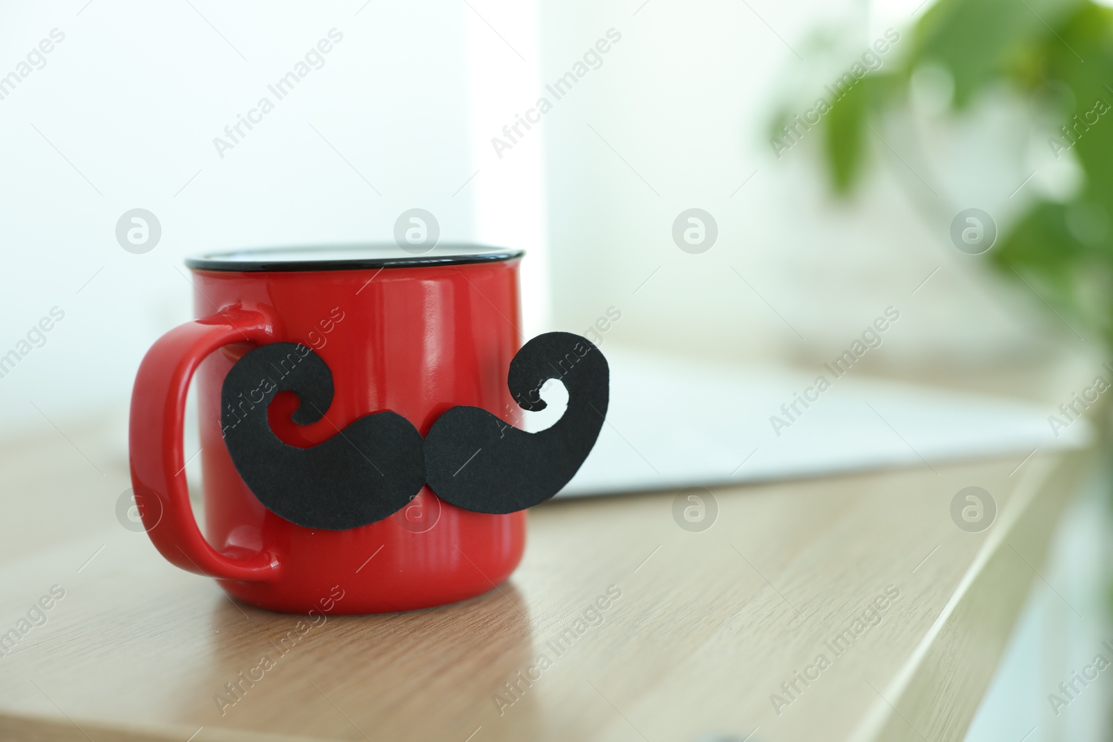 Happy Father's Day. Cup with mustache on wooden table indoors, closeup. Space for text Photo of Happy Father's Day. Cup with mustache on wooden table indoors, closeup. Space for text