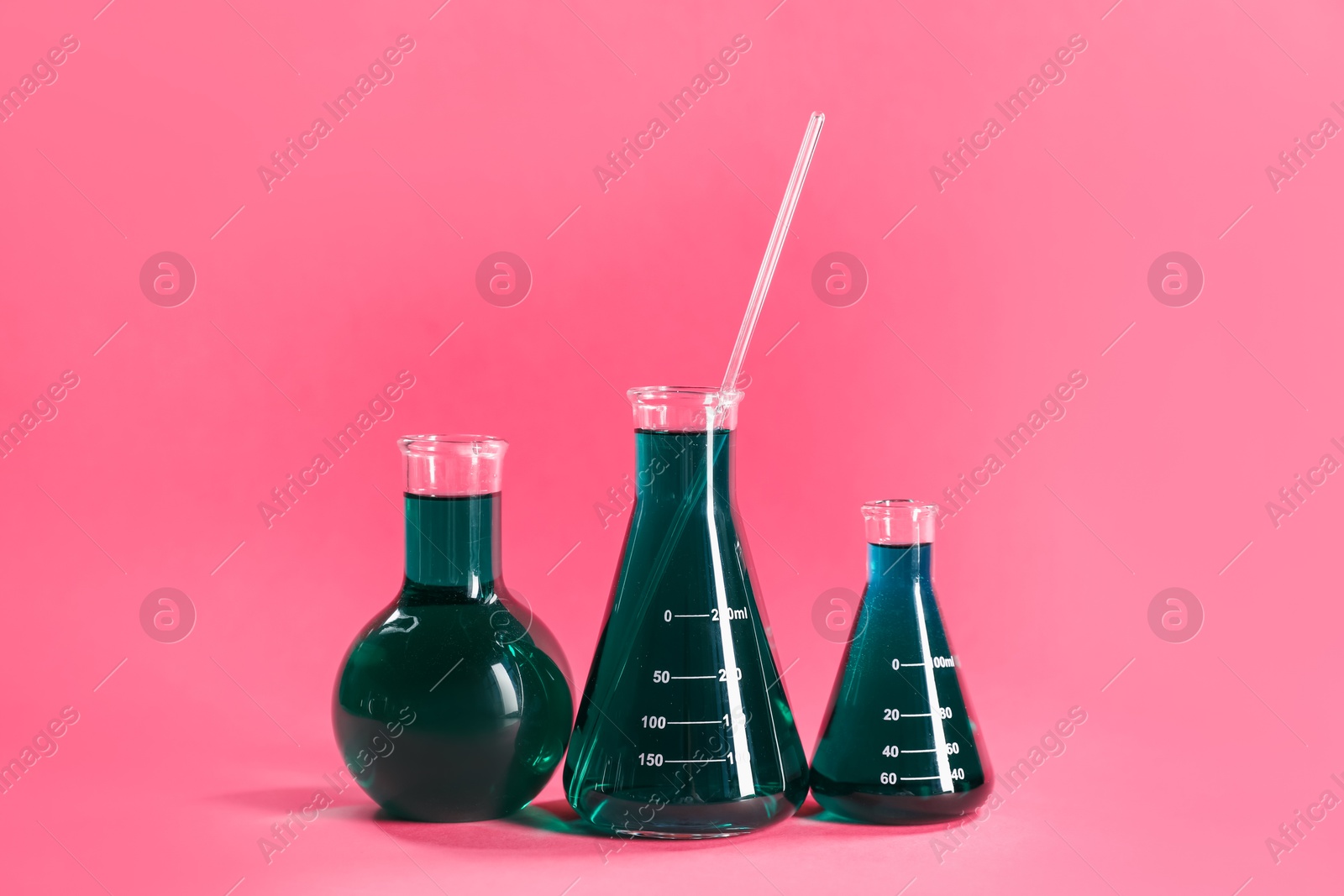 Photo of Laboratory glassware with green liquid on pink background