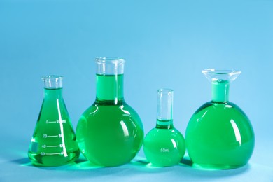 Photo of Laboratory glassware with green liquid on light blue background