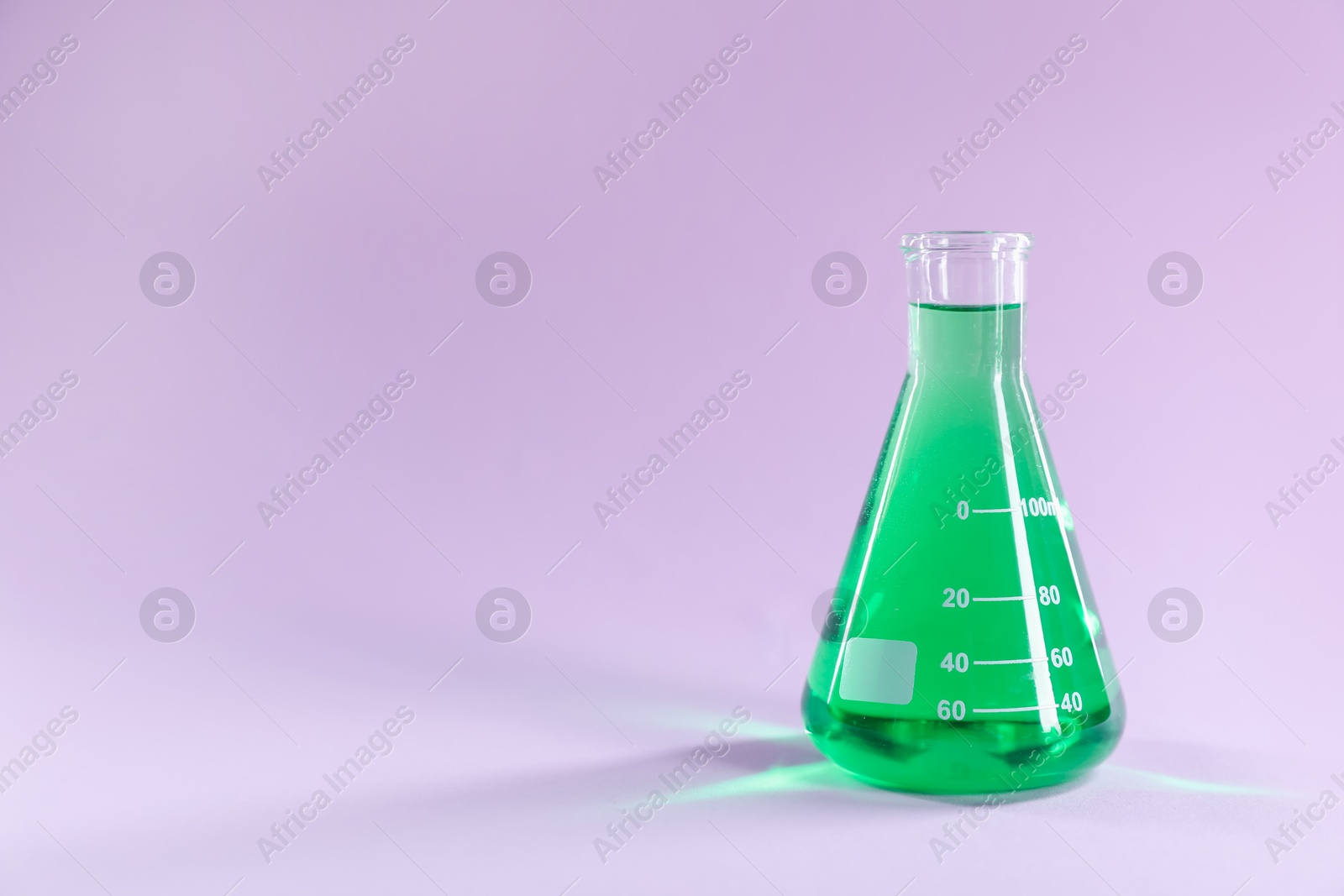 Conical flask with green liquid on lilac background. Space for text Photo of Conical flask with green liquid on lilac background. Space for text