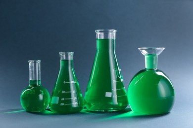 Photo of Laboratory glassware with green liquid on grey background